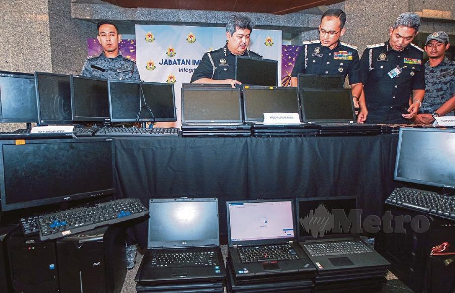 KHAIRUL Dzaimee (tiga dari kanan) melihat  barangan dirampas dalam serbuan sindiket penipuan pelaburan dalam talian di Cyberjaya pada sidang media yang di Ibu Pejabat Imigresen Putrajaya. FOTO Luqman Hakim Zubir