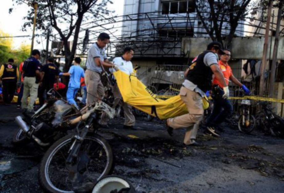 PASUKAN Paramedik membawa keluar mayat mangsa pengeboman bunuh diri berhampiran motorsikal yang terbakar di Gereja Pentecost, Surabaya Tengah, semalam. - FOTO/ REUTERS