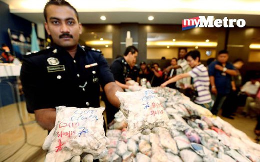 PEGAWAI polis menunjukkan dadah yang dirampas dan dibungkus seperti nasi kandar. 