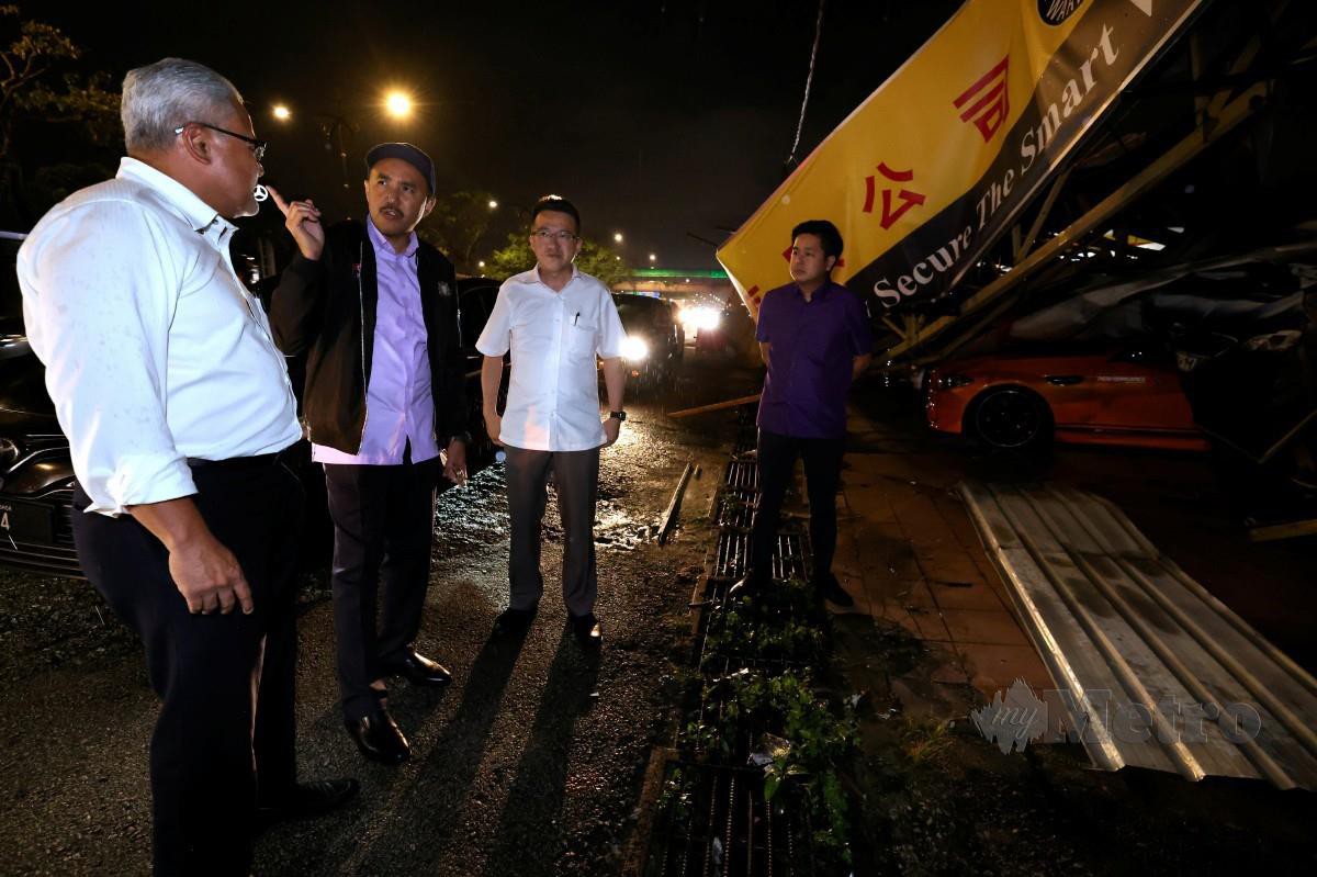 JAFNI (dua, kiri) bersama Mohd Noorazam (kiri) dan Chin Tong (dua kanan) melihat kedai kereta terpakai yang mengalami kerosakan akibat ribut. FOTO Bernama 