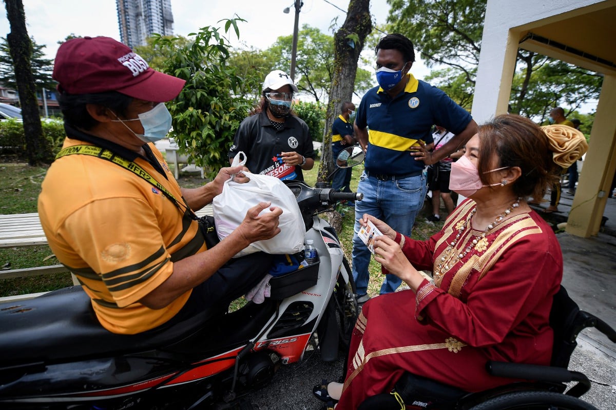 Ras Adiba (kanan) menyampaikan sumbangan keperluan harian dan baucer kepada bekas atlet paralimpik di Petaling Jaya. FOTO Bernama