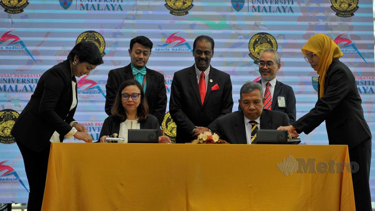 SIVASUNDARAM (berdiri tengah) menyaksikan MoU ditandatangani Dr Nazirah (duduk kiri) dan Penolong Setiausaha Agung FAM, Rosman Mohd Ibrahim (duduk, kanan) di Bangunan Plaza PPUM Kuala Lumpur, hari ini. FOTO BERNAMA 