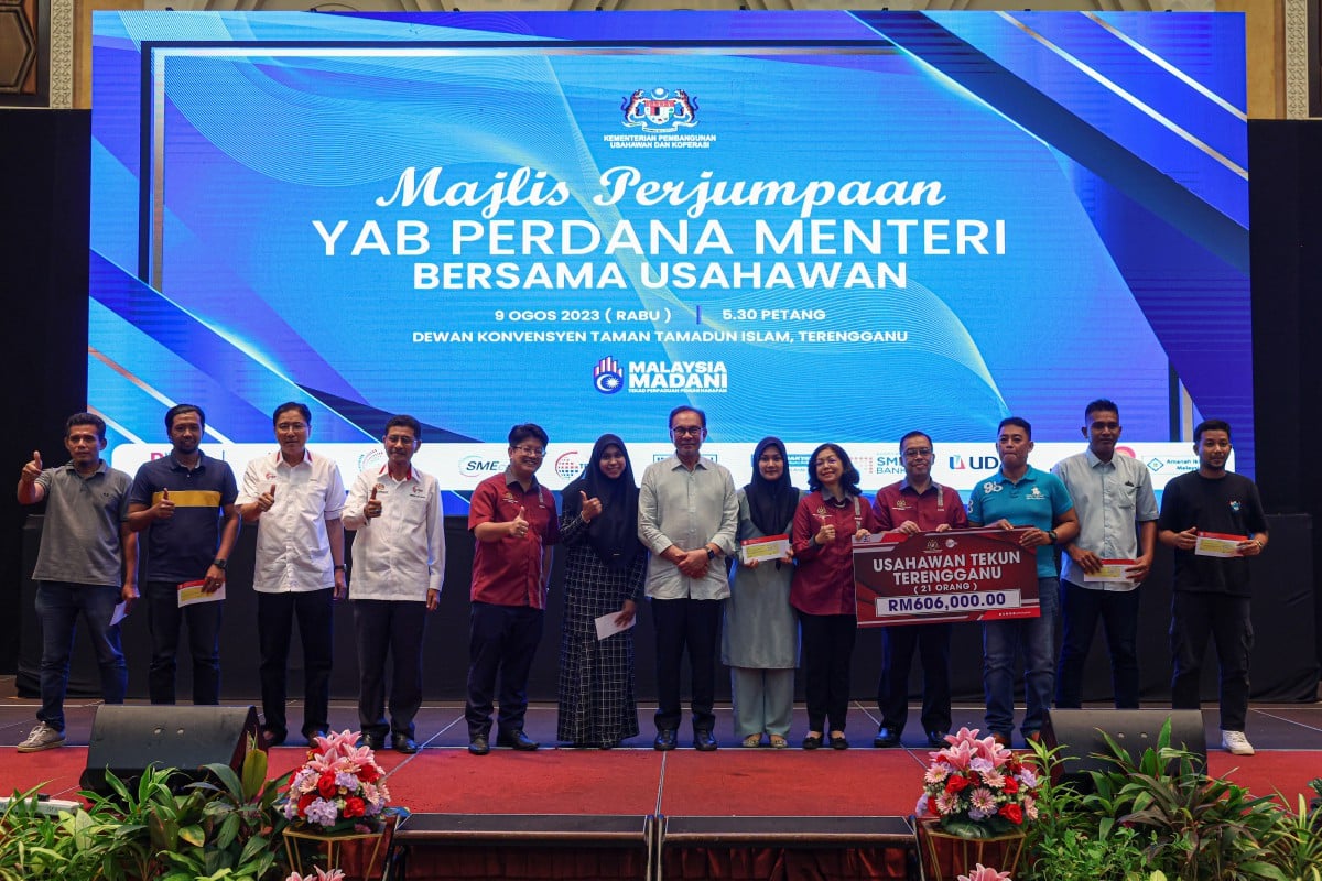 ANWAR dan Ewon (lima, kiri) bergambar bersama sebahagian penerima cek Skim Pembiayaan Usahawan Tekun Negeri Terengganu. FOTO Bernama 