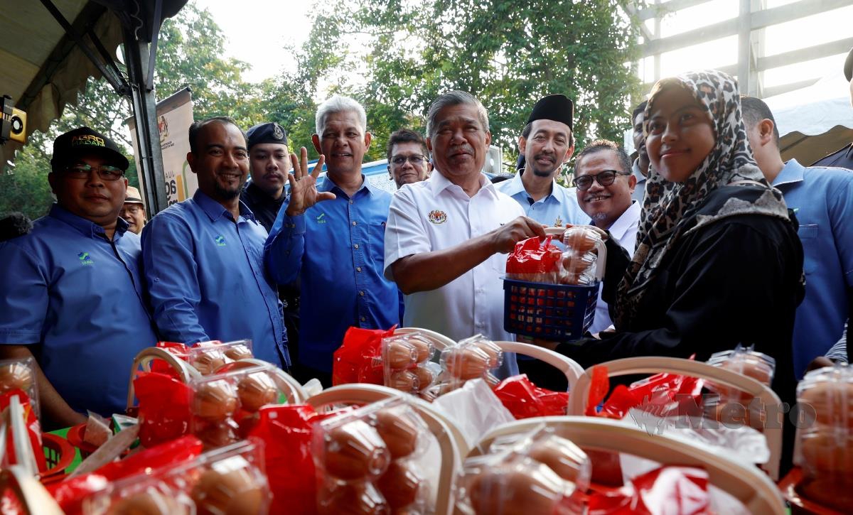 Mohamad Sabu (tengah) menyerahkan bakul makanan kepada pembeli pada Majlis Pelancaran Semarak Syawal Agro MADANI Peringkat Kebangsaan di Pasar Tani Taman Sri Andalas, hari ini. FOTO BERNAMA