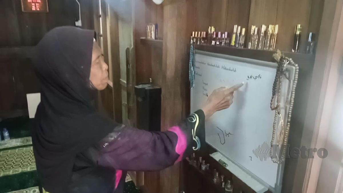 Seorang warga emas, Sharifah Mariam, 76, menunjukkan tulisan Nabi Khidir pada papan tanda dalam surau Tok Ku Paloh. FOTO BAHAROM BAKAR.