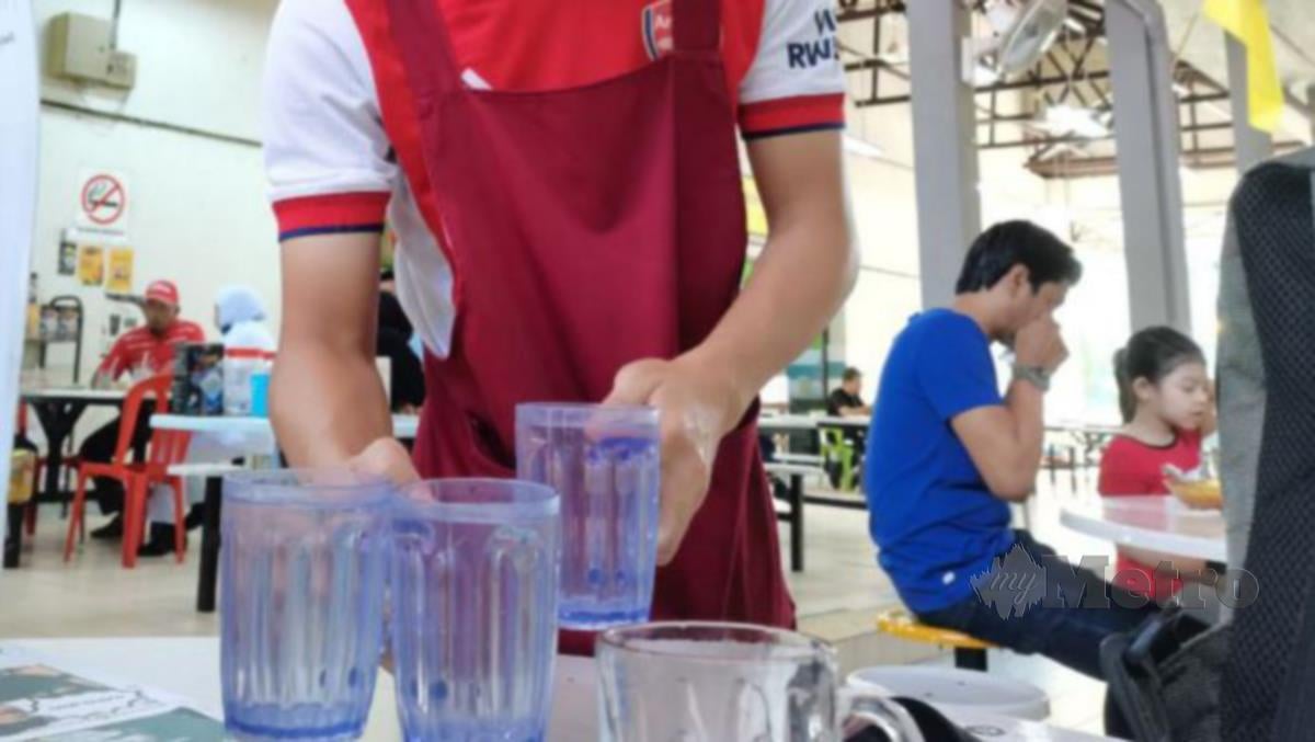 PELAYAN kedai makan di Medan Selera Penghulu Cantik, Seremban menghantar air suam kepada pelanggan.