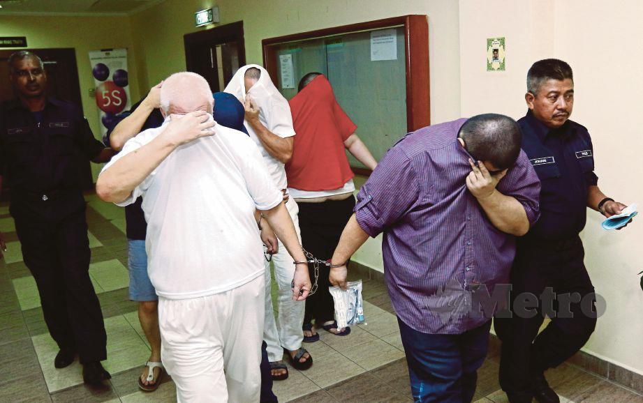 ANGGOTA polis mengiringi enam tertuduh kes menjual dokumen pengenalan diri termasuk sijil kelahiran dan MyKad di Mahkamah Tinggi Pulau Pinang, Georgetown, hari ini. FOTO Mikail Ong.