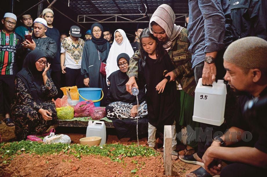 FARAH dan anak bongsunya menyiramkan air mawar ketika pengebumian jenazah suaminya di Tanah Perkuburan Islam AU2 Keramat pagi ini. FOTO MOHD SAFWAN MANSOR