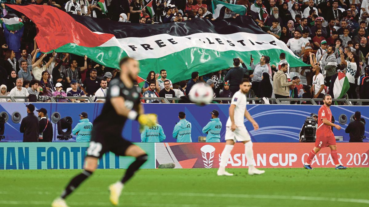 BENDERA Palestin dikibarkan ketika Iran menang 4-1 ke atas Palestin pada aksi Piala Asia, awal pagi tadi. FOTO AFP 