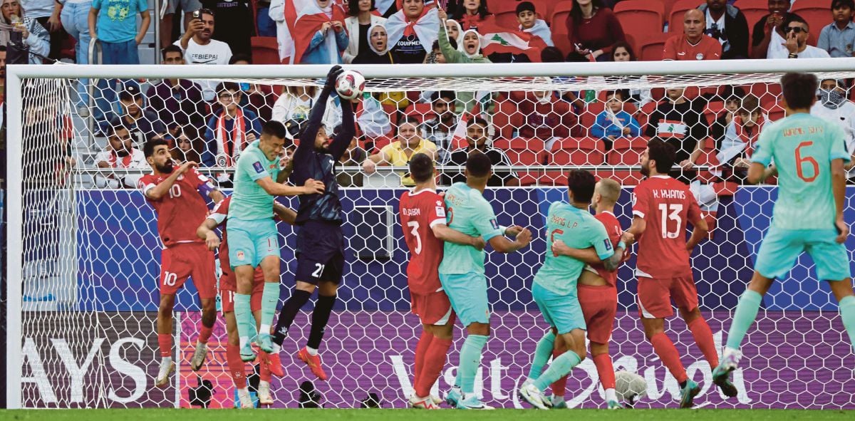 PENJAGA gol Lubnan  Mostafa Matar menyelamatkan bola sebelum ditanduk penyerang China Tan Long. FOTO AFP 