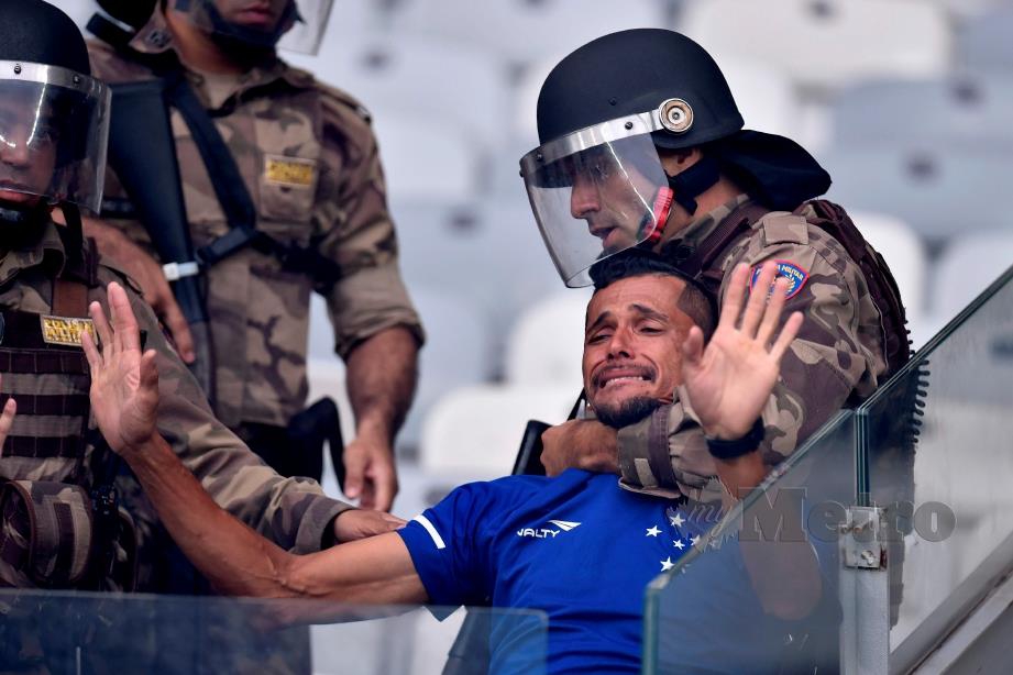 POLIS menahan seorang penyokong Cruzeiro di Stadium Mineirao. FOTO AFP