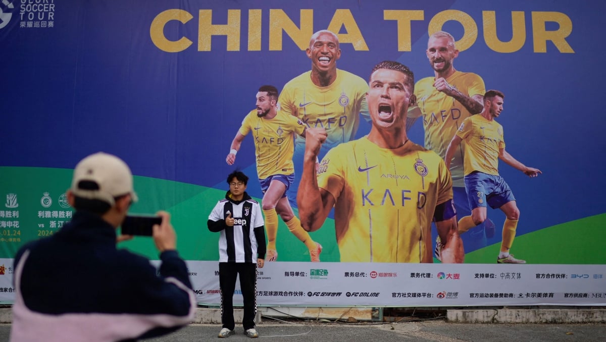 PEMINAT Ronaldo bergambar di depan poster Jelajah China di Pusat Sukan Universiade di Shenzhen. FOTO AFP 