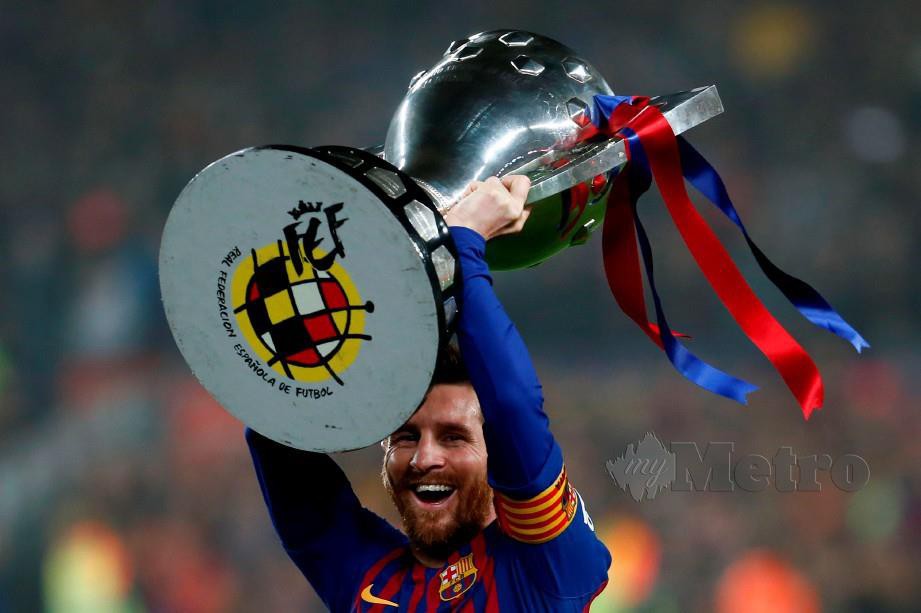 Penyerang Barcelona Lionel Messi meraikan bersama trofi La Liga. FOTO AFP.
