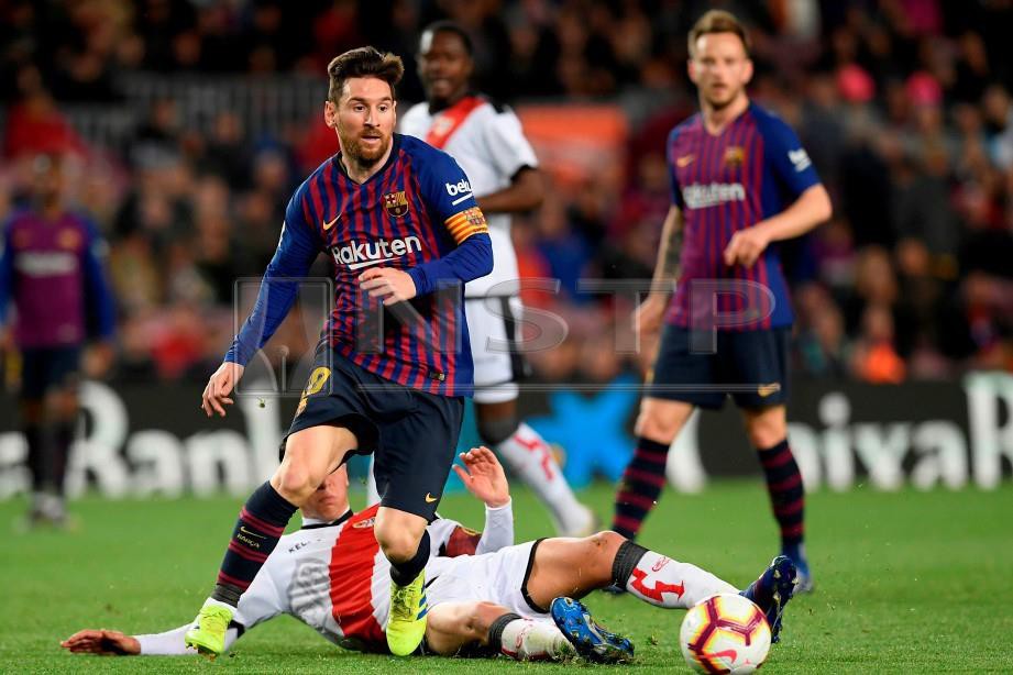 Pemain Barcelona Lionel Messi (kiri) melepasi halangan pemain Rayo Vallecano Santi Comesana dalam aksi La Liga di Stadium Camp Nou. FOTO AFP.