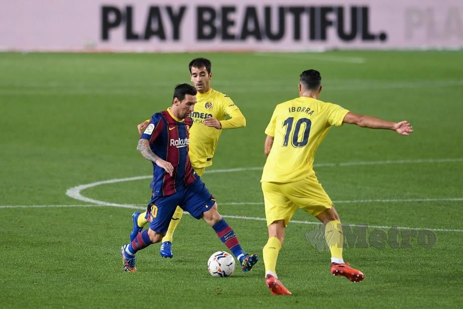 Lionel Messi mengatasi dua pemain Villarreal pada aksi La Liga. FOTO AFP