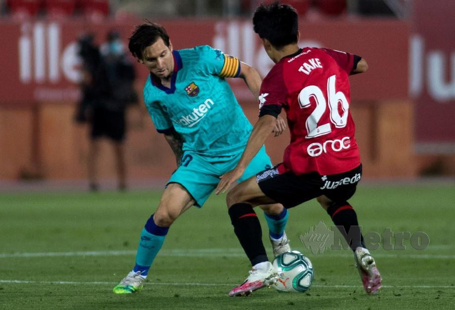 MESSI (kiri) menerima cabaran daripada pemain tengah Mallorca, Takefusa Kubo. FOTO AFP