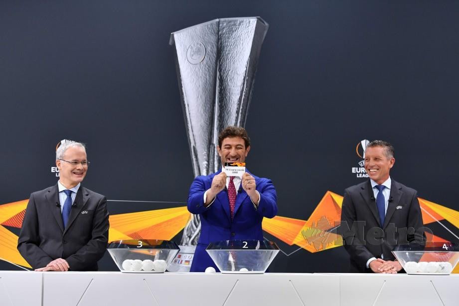 Bekas pertahanan Napoli, Ciro Ferrara menunjukkan kad undian sambil diperhatikan Presiden UEFA, Aleksander Ceferin (kanan) dan Pengarah kejohanan UEFA, Giorgio Marchetti (kiri) ketika majlis undian peringkat kumpulan di Nyon. FOTO AFP 
