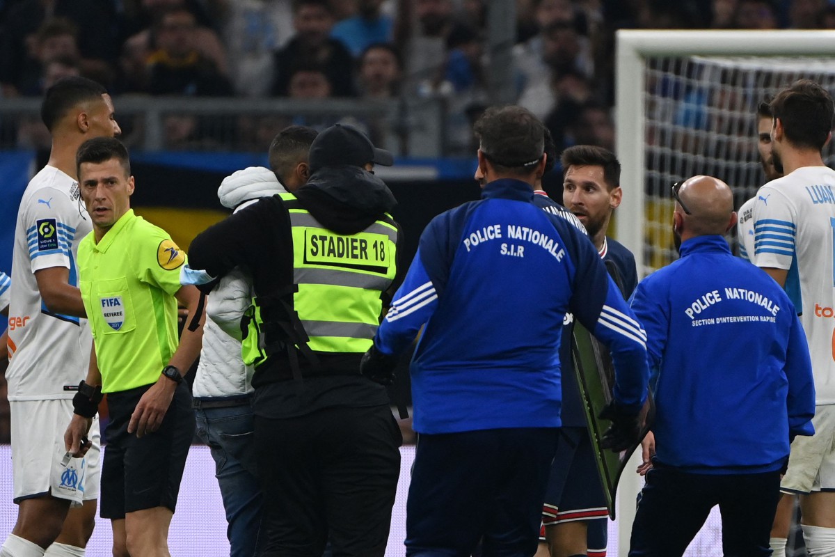 Anggota keselamatan menahan seorang penonton yang menceroboh padang dan mendekati penyerang PSG, Lionel Messi (tiga kanan) pada aksi Ligue 1 di Marseille. FOTO AFP