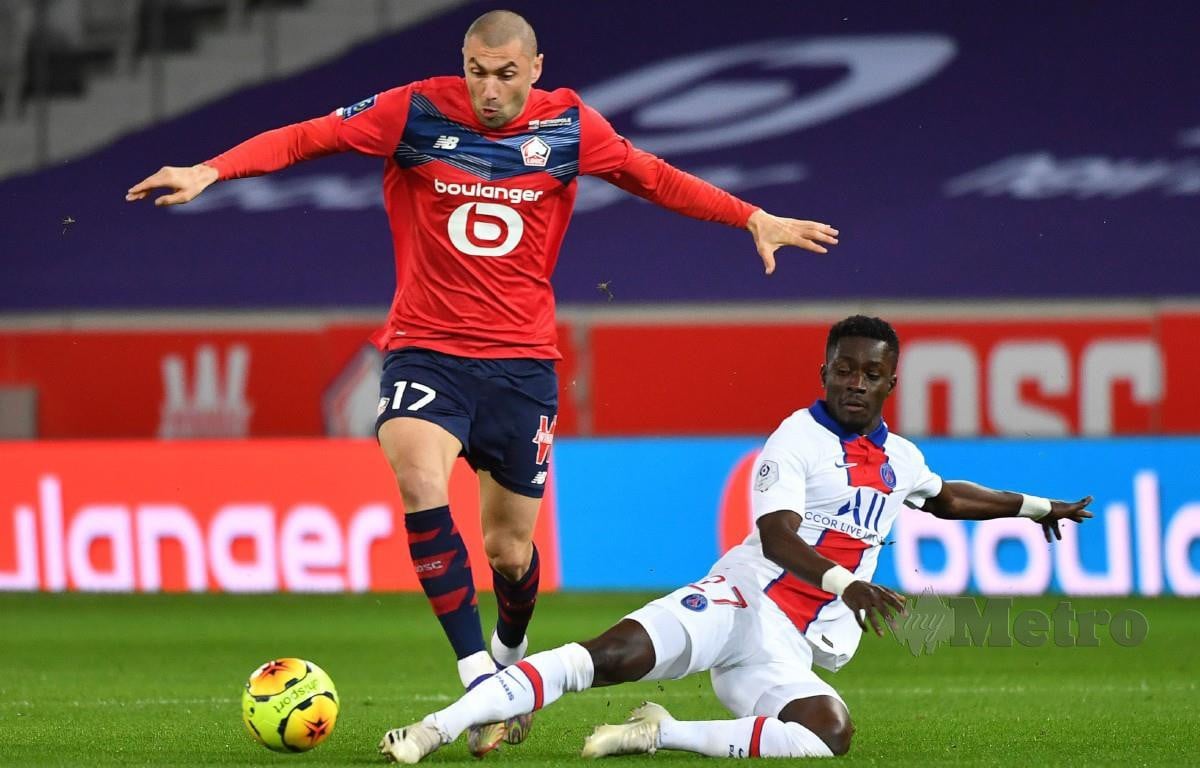PENYERANG Lille, Burak Yilmaz (kiri) cuba melepasi halangan pemain tengah PSG, Idrissa Guaye dalam aksi Ligue 1. FOTO AFP