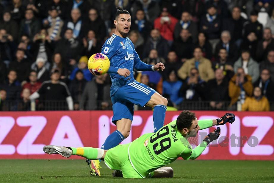 RONALDO mencabar penjaga gol SPAL, Etrit Berisha pada perlawanan Serie A, Sabtu lalu. FOTO AFP