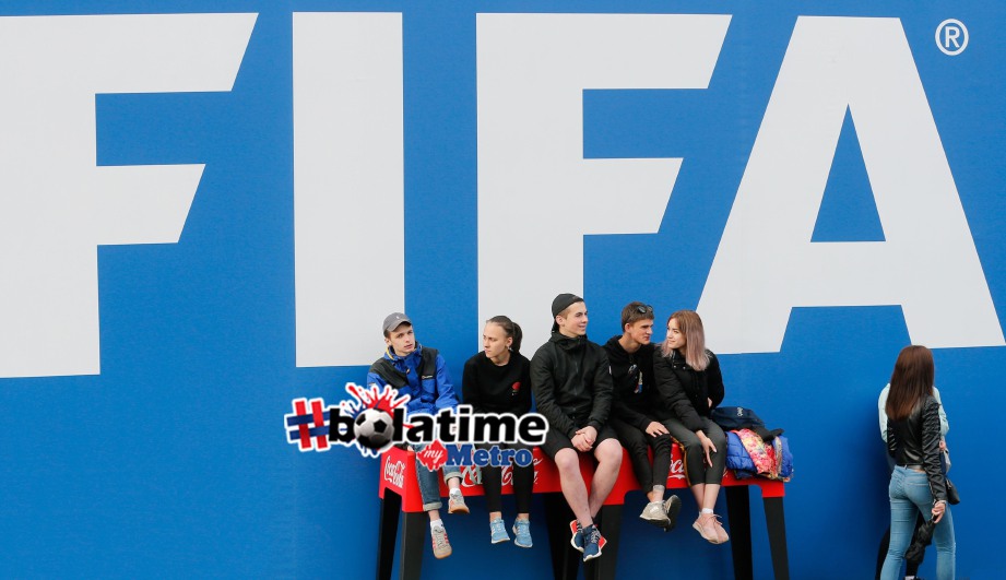 ORANG ramai duduk di hadapan logo FIFA menjelang aksi pembukaan Piala Dunia di Russia. FOTO AFP