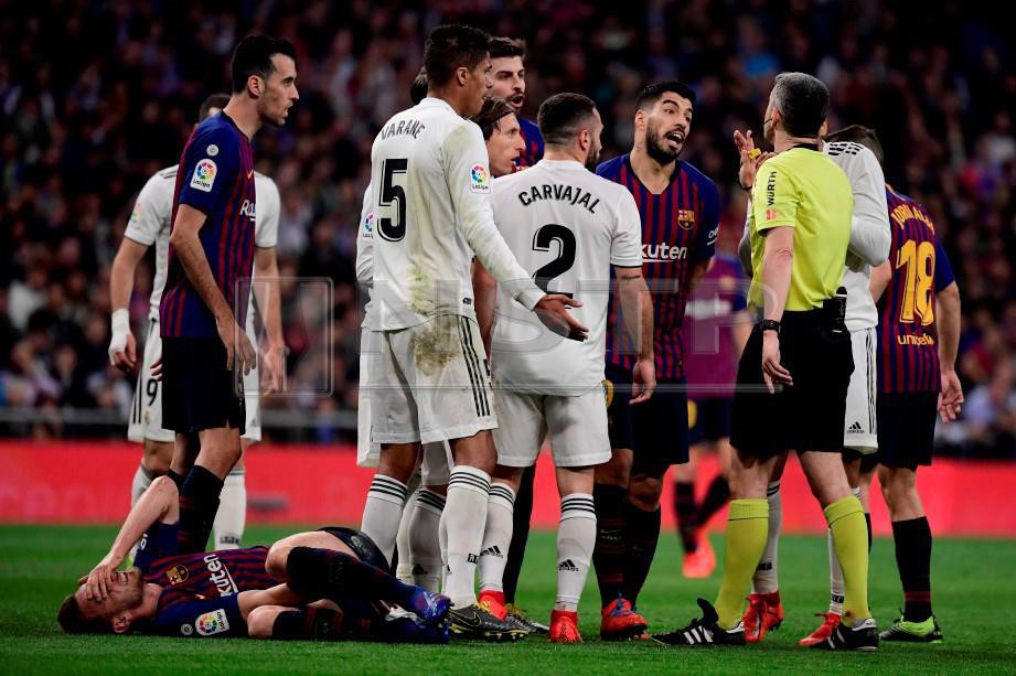  Aksi tegang antara pemain Barcelona dan Real Madrid. FOTO AFP.