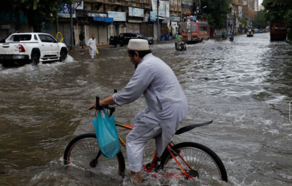 LELAKI mengayuh basikal ketika banjir kilat di Karachi, pada 25 Julai 2022. FOTO Reuters