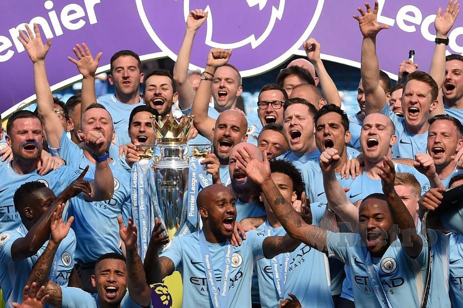 Pemain Manchester City bersama pengurusnya Pep Guardiola (tengah) memegang trofi Liga Perdana ketika muncul juara musim lalu. FOTO FILE AFP.
