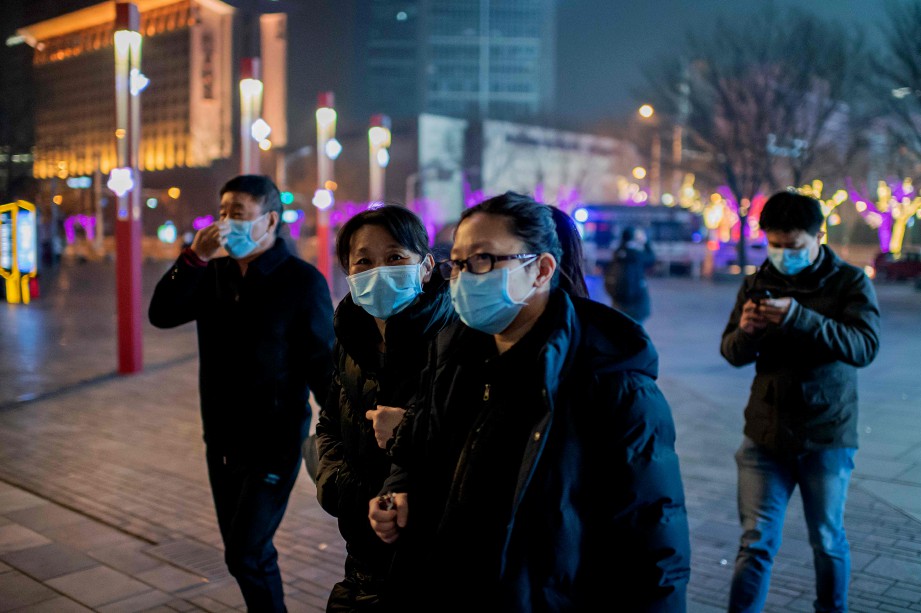 ORANG awam memakai penutup mulut dan hidung ketika berjalan di pusat beli-belah di Beijing. FOTO AFP