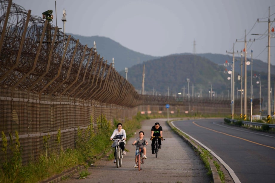 FOTO fail menunjukkan penduduk Korea Selatan menunggang basikal berhampiran pagar kawat duri Zon Bebas Tentera (DMZ) yang memisahkan negara itu dengan Korea Utara. FOTO AFP 