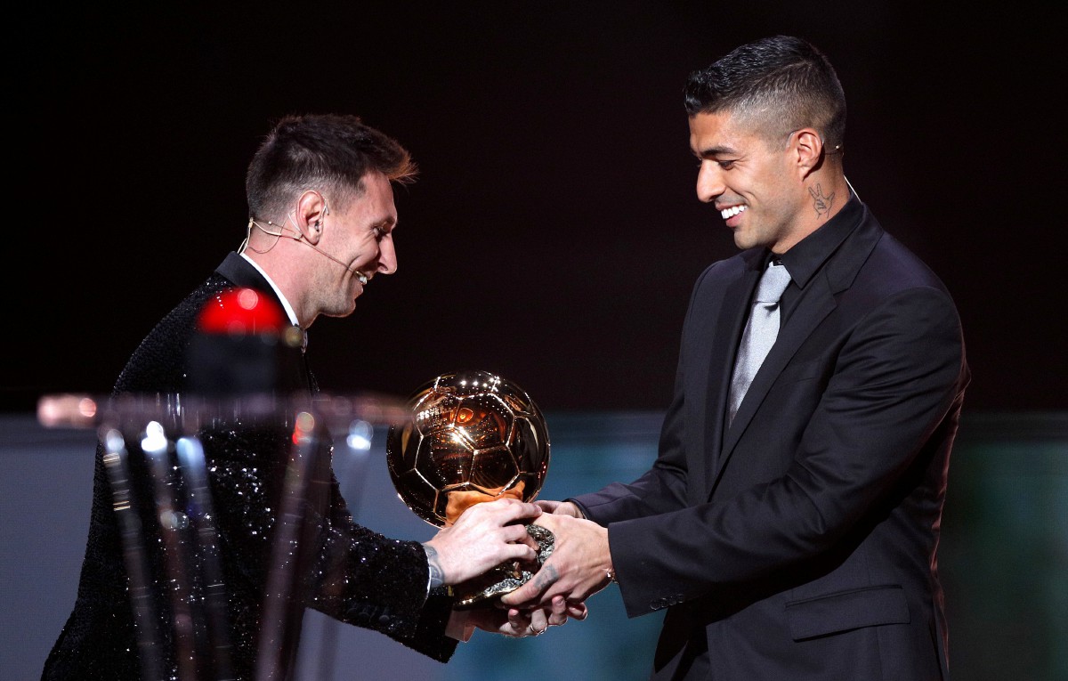 Lionel Messi (kiri) menerima anugerah Ballon d'Or dari bekas rakan sepasukan di Barcelona, Luis Suarez. FOTO EPA