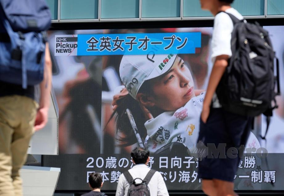 ORANG ramai berjalan melewati skrin gergasi yang melaporkan kejayaan Hinako di Tokyo. - FOTO  AFP