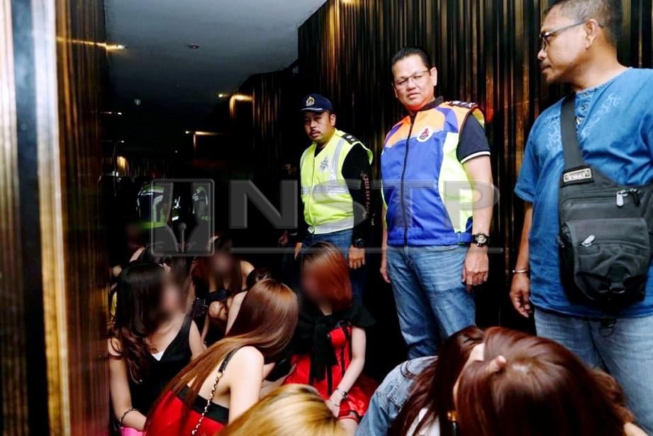AZMAN (berdiri tengah) melakukan pemeriksaan dokumen terhadap warga asing yang ditahan dalam serbuan di pusat hiburan di Jalan Ampang, Kuala Lumpur, awal pagi hari ini. FOTO ihsan DBKL.