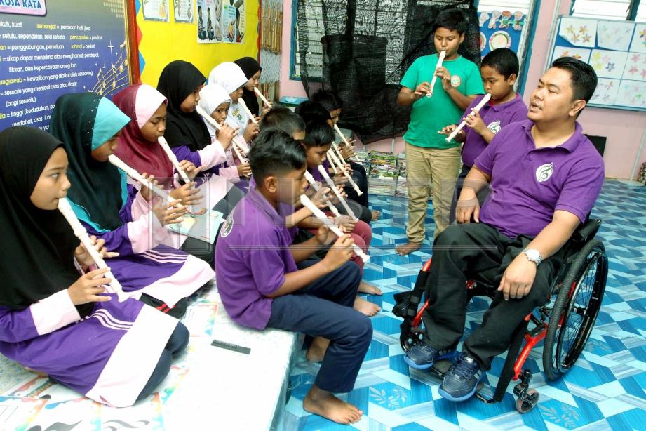 MOHD Huzaire mengajar anak muridnya bermain alat muzik di Sekolah Kebangsaan (SK) FELDA Mempaga 2, Bentong. Foto MOHD RAFI MAMAT.