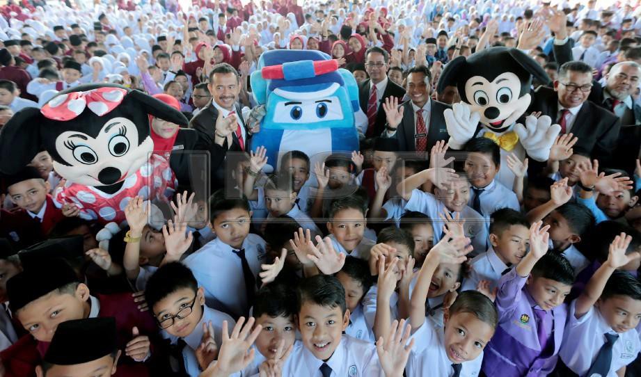 Murid-murid Sekolah Kebangsaan Kubang Kerian (3) bergambar bersama tiga watak kartun Mickey, Minie Mouse dan Robocarpoli di hari pertama persekolahan. FOTO Fathil Asri