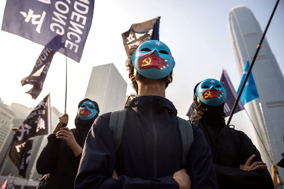 AKTIVIS memegang sepanduk dan mengenakan topeng sepanjang perhimpunan solidariti di Hong Kong. FOTO AFP