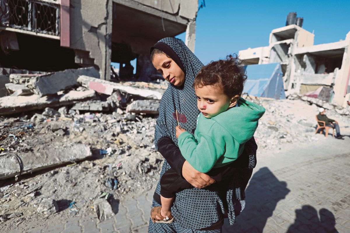 WANITA Palestin mendukung kanak-kanak, ketika berlindung di sebuah kem di Gaza. FOTO Reuters 