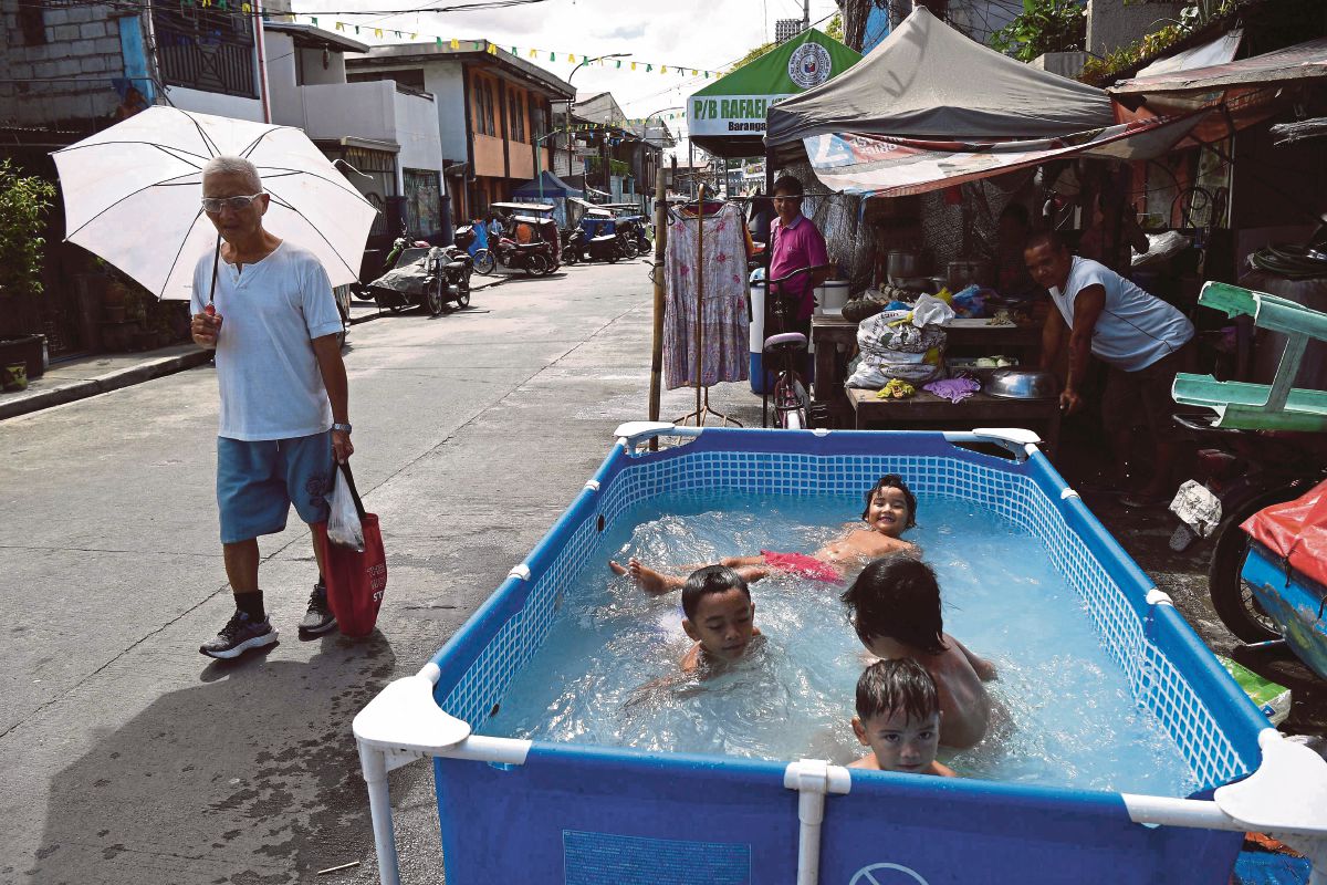 KANAK-KANAK menyejukkan diri dengan mandi di dalam kolam ketika cuaca panas di Manila. FOTO AFP