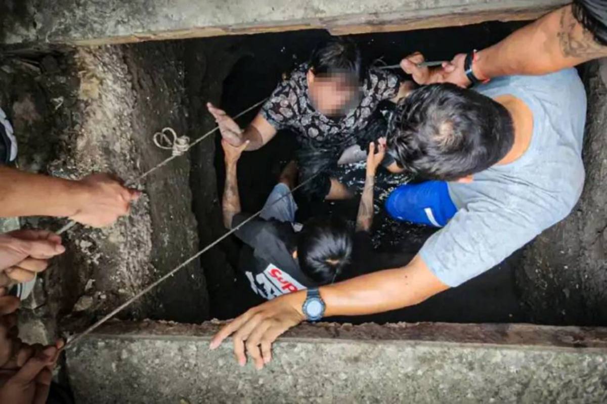 WIPARAT (tengah) diselamatkan selepas terjatuh di dalam lubang saliran. FOTO The Nation 