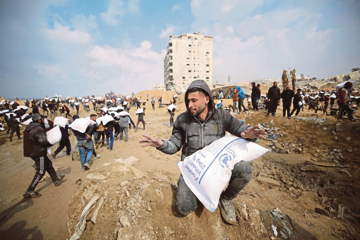 PENDUDUK Palestin membawa guni berisi tepung yang diambil trak bantuan. FOTO Reuters 