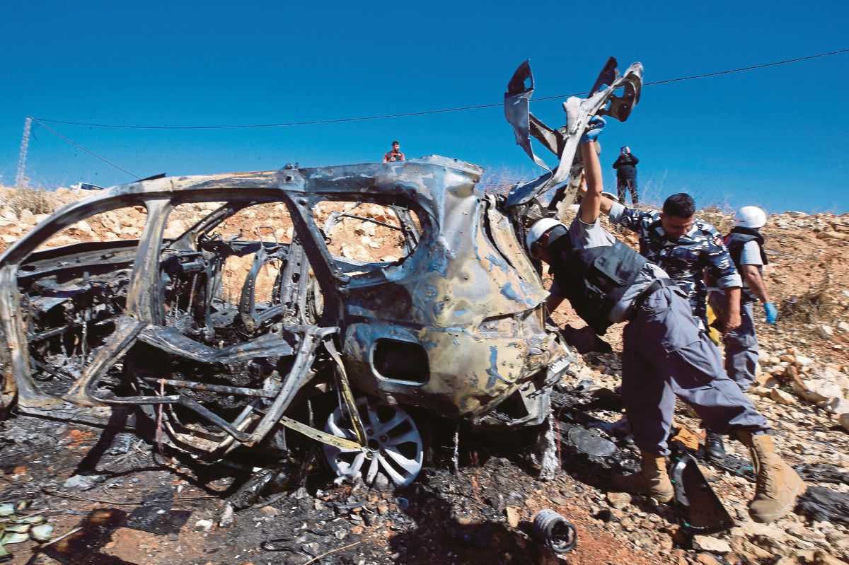 FOTO fail menunjukkan pasukan penyelamat dari Hizbullah memeriksa kenderaan yang musnah susulan serangan udara Israel di selatan Lubnan. FOTO AFP 