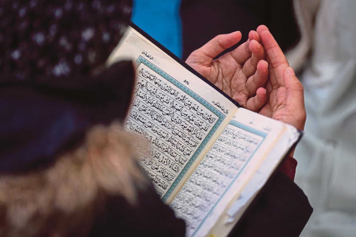JEMAAH yang hadir turut membaca al-Quran. FOTO AFP