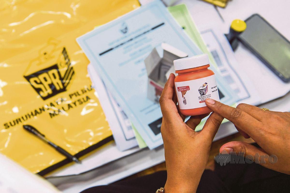 PETUGAS SPR melakukan pemeriksaan maklumat pada botol dakwat kekal semasa membuat persediaan kit peralatan pusat mengundi sebelum dibawa ke pusat mengundi di Dewan Dato' Bahaman, Kuala Pilah, semalam. FOTO Bernama