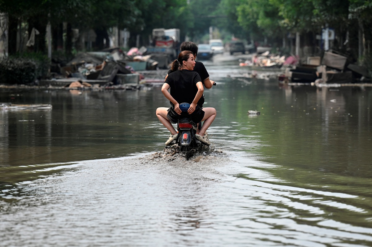 PENDUDUK menaiki skuter di jalan yang dinaiki air di bandar Zhuozhou, wilayah Hebei, utara China pada 9 Ogos lalu. FOTO AFP 