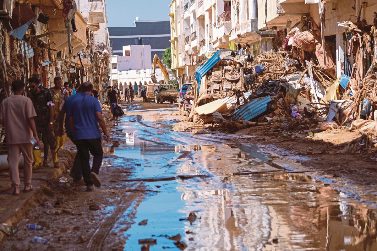 ORANG ramai berjalan di kawasan yang terjejas susulan banjir besar di Derna, Libya. FOTO Reuters 
