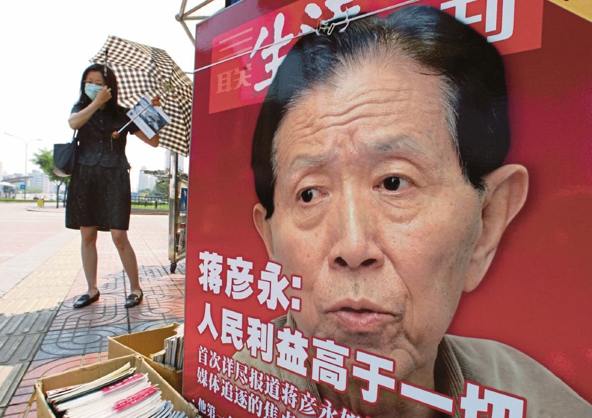 WANITA membetulkan pelitup mukanya berhampiran poster memaparkan Dr Jiang Yanyong, di Beijing. FOTO fail Reuters. 