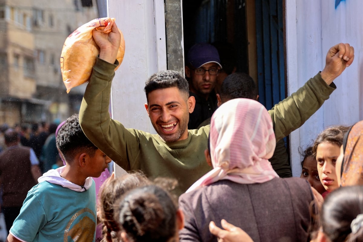 LELAKI Palestin gembira selepas dapat membeli roti bersubsidi di luar kedai roti di Gaza. FOTO AFP