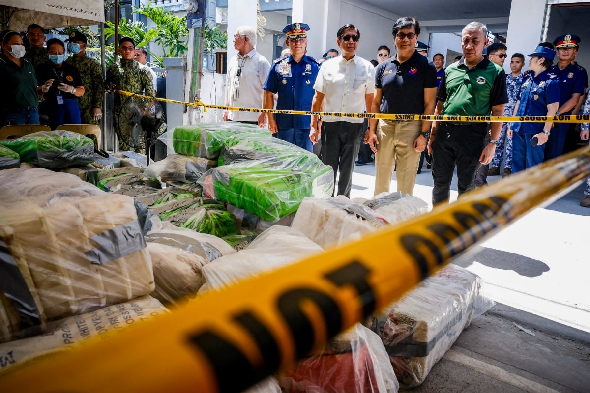 Marcos (tengah, berbaju putih) memeriksa rampasan dadah itu. FOTO AFP 