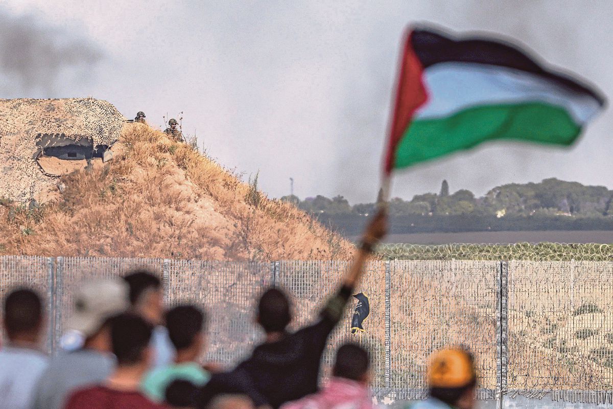 TENTERA Israel di sebalik kubu memerhatikan penduduk Palestin yang melakukan demonstrasi berhampiran pagar sempadan di Gaza, bagi membantah Perarakan bendera Israel di Baitulmaqdis. FOTO AFP