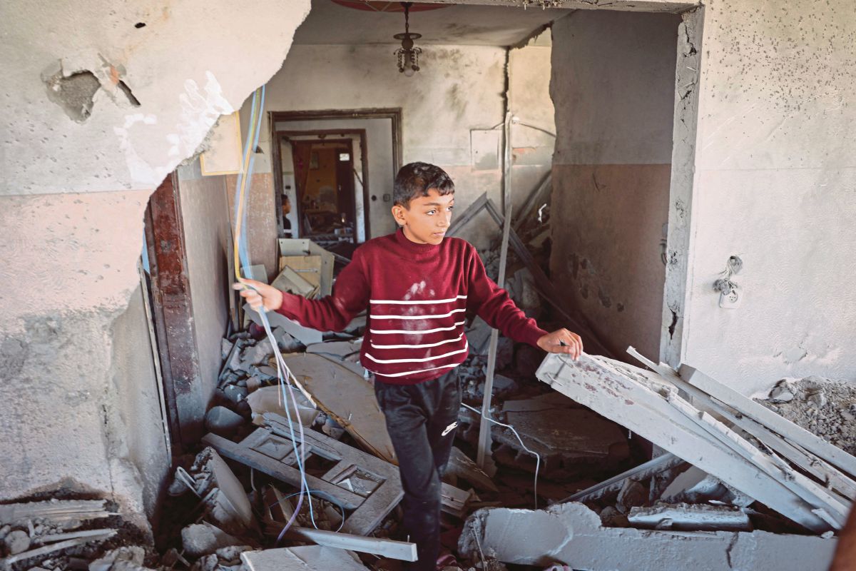 KANAK-KANAK Palestin memeriksa kerosakan pada rumah yang dibom Israel. FOTO AFP